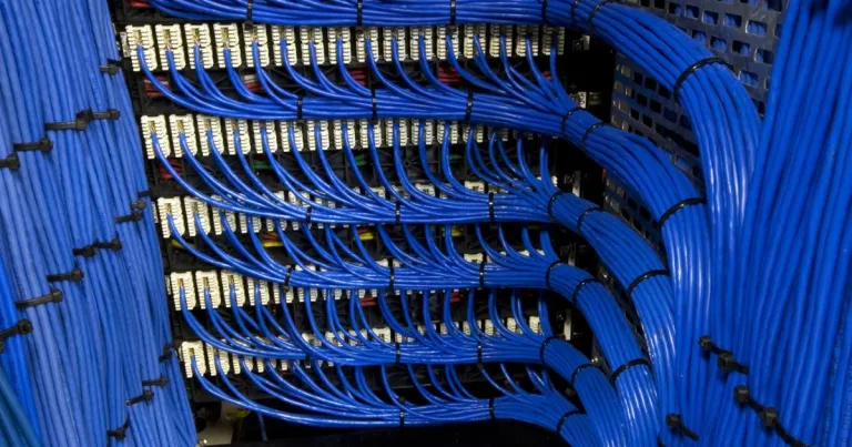 Rack com switches, patch panel e cabos organizados em infraestrutura de rede corporativa