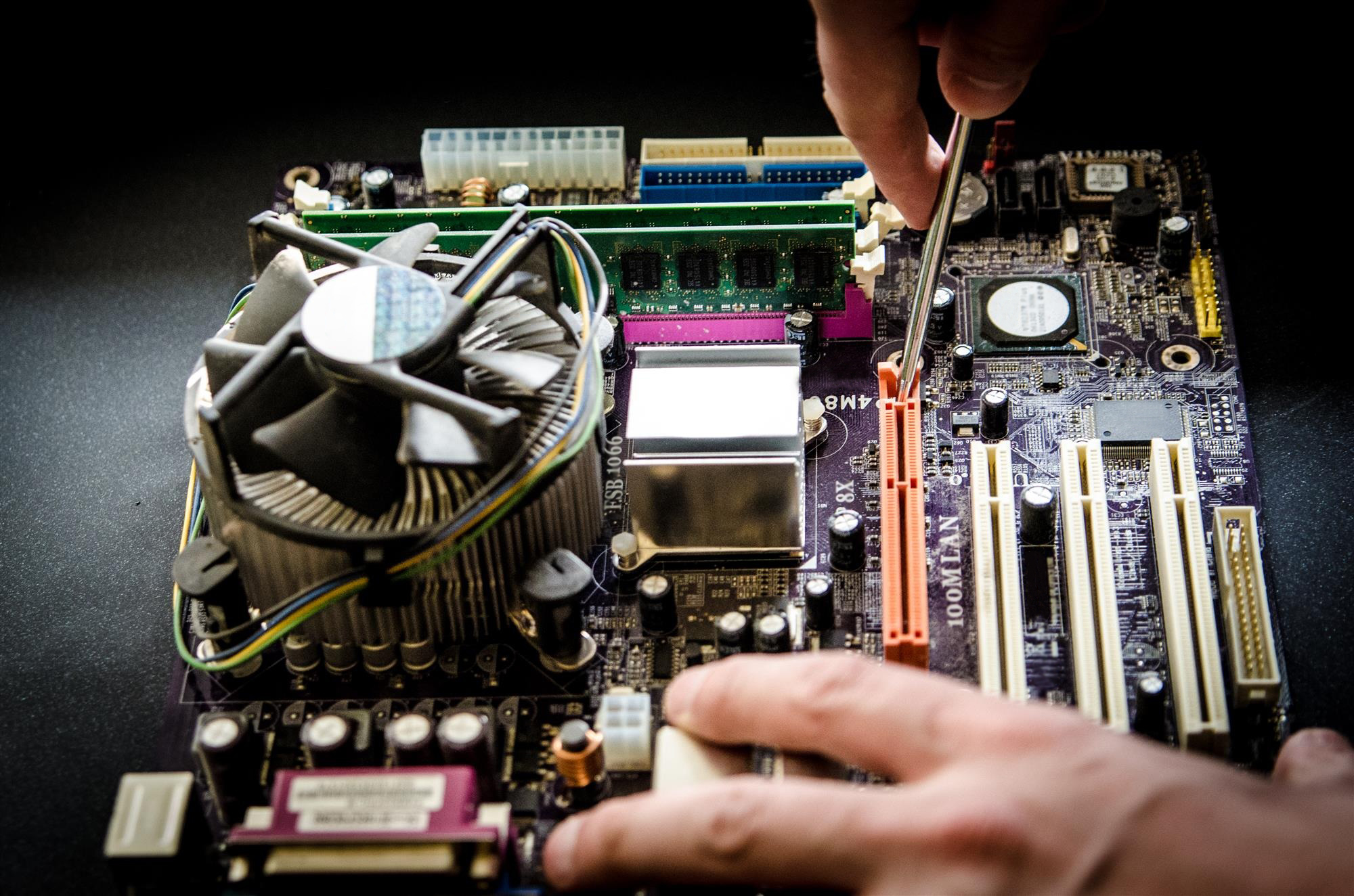 Técnico de TI realizando manutenção preventiva em um computador empresarial, verificando componentes internos e realizando limpeza